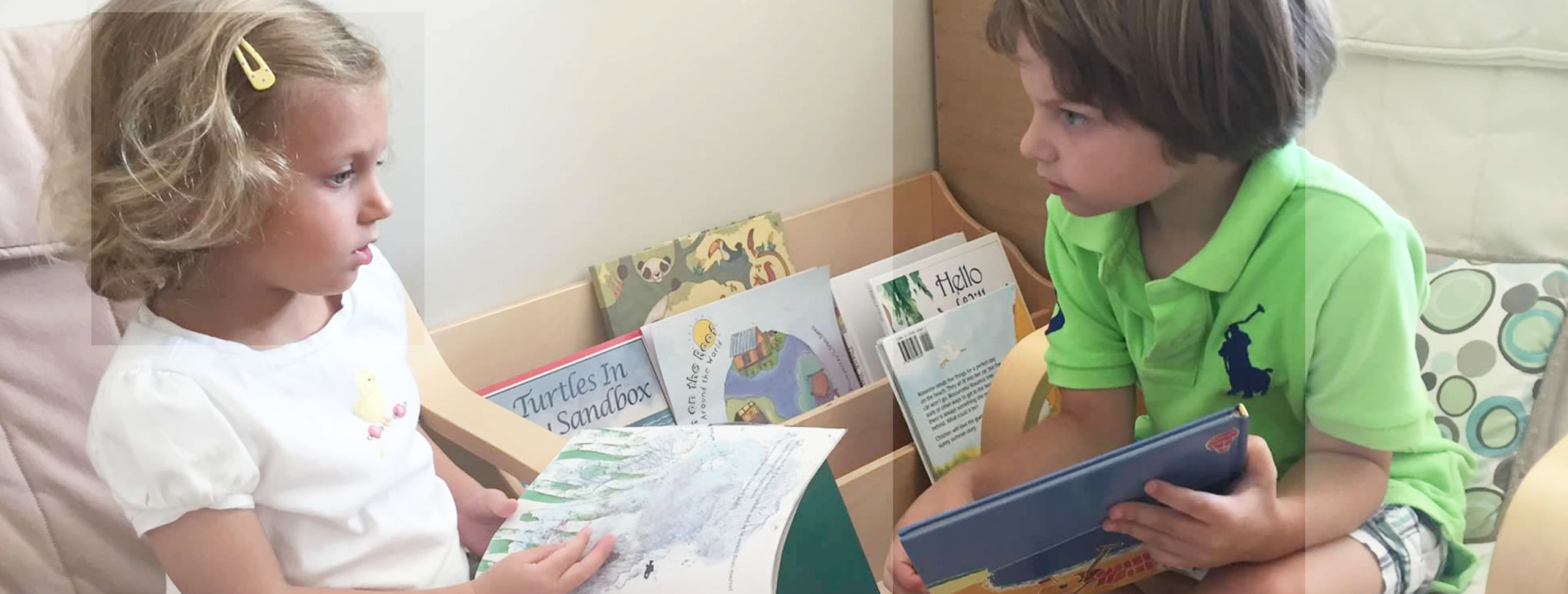 Two Montessori preschoolers read together and discuss a book.